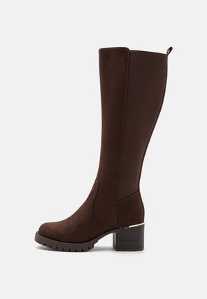 Botte marron hauteur genou en matériau doux et texturé avec un talon épais, dotée d'un accent métallique subtil et de panneaux latéraux élastiques pour un ajustement parfait.