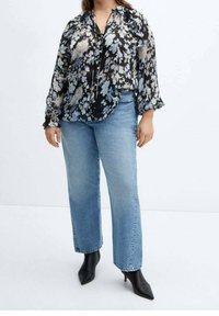 Black floral blouse with ruffled sleeves, paired with light blue straight-leg jeans. Model wears black pointed-toe boots.
