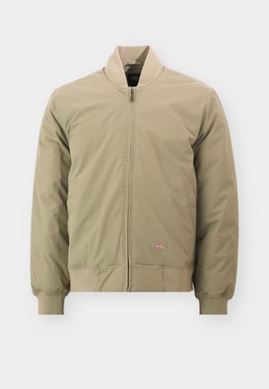 Svetlo khaki bomber bunda so zipsom, s rebrovanými manžetami a mäkkým golierom. Vyrobená z hladkej látky s malou nášivkou loga na hrudi.