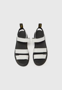 Witte leren sandalen met drie verstelbare klittenbandsluitingen, een textuur zwarte zool en een gele trekhaak aan de hiel. Casual open ontwerp.