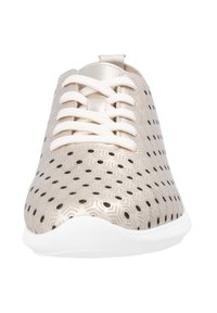 Beżowe sneakersy z perforowanymi geometrycznymi wzorami, płaską białą podeszwą i dopasowanymi sznurówkami. Gładka tekstura z metalicznym połyskiem i zaokrąglony czubek.
