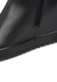 Stivaletto in pelle nera con finitura texture, zip laterale e suola in gomma con un battistrada pronunciato e marchio impresso.