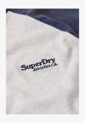 T-shirt en coton gris et marine avec "SuperDry Athletics.CA" brodé en marine sur la poitrine, texture lisse avec une finition légèrement chinée.