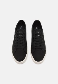 Černé plátěné tenisky s texturovaným povrchem, vybavené bílými gumovými podrážkami a tkaničkami. Logo vytištěné na vložce. Klasický nízký střih.