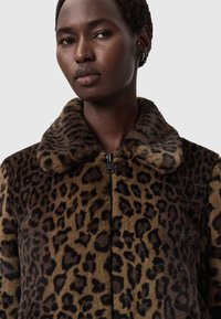 Leoparda raksta mākslīgā kažokādas jaka ar mīkstu tekstūru, tumši brūnās un brūnas krāsas, ar apkakles dekoltē un priekšējo rāvējslēdzēju.