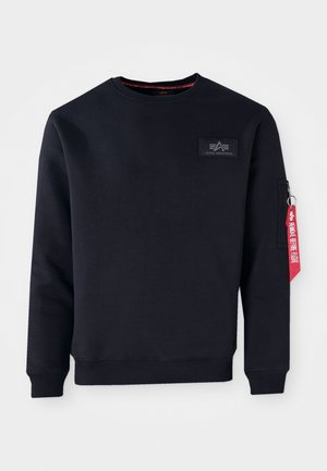 Sudadera de color azul marino oscuro hecha de una mezcla de algodón, con cuello redondo, puños acanalados y un bolsillo con cremallera en la manga que presenta una etiqueta roja.