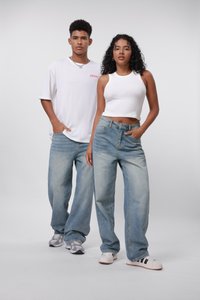 Lyseblå baggy jeans med en falmet finish, kombinert med en hvit ribbet crop top og en løs hvit t-skjorte. Joggesko fullfører antrekket.