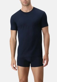 T-shirt aderente blu navale a maniche corte, realizzato in un tessuto morbido. Pantaloni corti blu navale complementari visibili in vita. Texture liscia.
