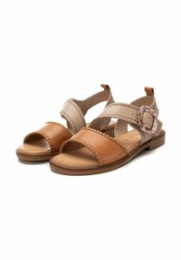 Sandalias de cuero marrón y beige con correas anchas, detalles de costura y una hebilla decorativa. Suela plana y diseño de punta abierta.