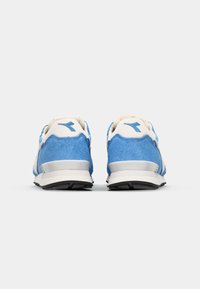 Scarpe da ginnastica blu scamosciate con dettagli bianchi e suola argentata, dotate di un collare imbottito e materiali texturizzati per il comfort.