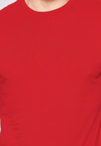 T-shirt rouge à col rond et manches courtes en coton, texture lisse avec un design ajusté, sans logos ni motifs visibles.