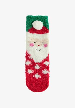 Chaussettes pelucheuses rouges et blanches avec un visage de Père Noël, un haut vert avec pompon et des motifs blancs. Texture douce, design sur le thème des fêtes.