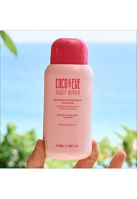 Coco & Eve Sweet Repair schampo-flaska, ljusrosa plast med ett rosa lock, med text som handlar om att reparera och återställa skadat hår. 280 mL.
