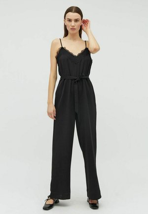 Sort jumpsuit med tynde stropper og blonder detalje ved udskæringen. Har en belagt talje og vide ben. Silkeagtig overflade.