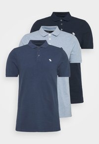 Tre polo shirt sono esposti: uno blu scuro, uno blu chiaro e uno a righe blu. Ognuno ha un colletto e tre bottoni, con un logo.