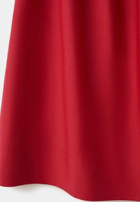 Rideau en tissu rouge suspendu droit, présentant de légers plis et un ourlet cousu en bas sur un fond blanc.