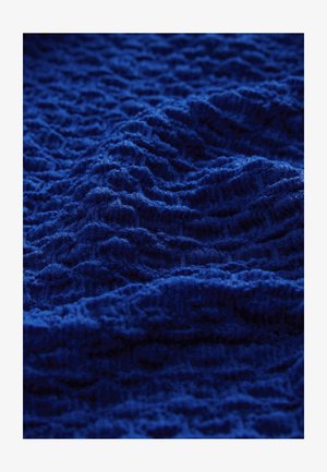 Blue textured fabric with wavy patterns, featuring a soft, knitted appearance. The material has a rich, deep color throughout.
