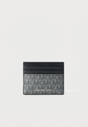 Small rectangular Michael Kors cardholder with black top slot section and grey patterned bottom with brand name in gold lettering.