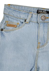 Light blue denim jeans with a textured finish, featuring yellow stitching, a branded leather patch, and a metallic button closure.