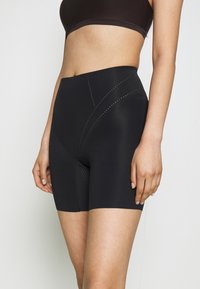 Black compression shorts with a high waistband, made of smooth material featuring curved, perforated designs along the sides.