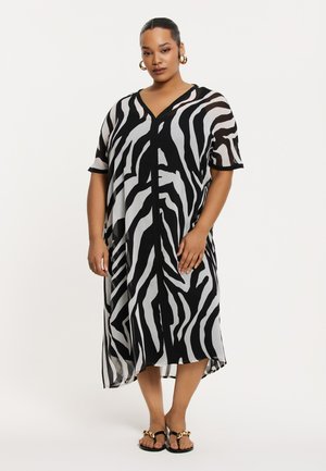 Robe maxi à rayures zèbre en noir et blanc, à manches courtes, décolleté en V, en tissu léger et transparent, atteignant le milieu du mollet, complétée par une ouverture à l'avant.