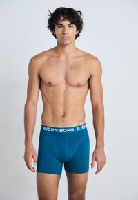 Túrós boxeralsó, fehér derékrésszel, rajta a "BJÖRN BORG" logóval. Puha, sima anyag, testhezálló fazon, comb közepéig ér.