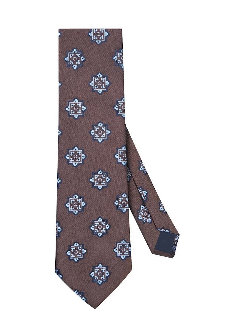 Brązowy krawat z powtarzającym się geometrycznym wzorem w niebieskim i białym kolorze, wykonany z gładkiego materiału, z ostrym końcem i małą metką.