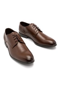 Pantofi de dress din piele maro, cu o textură netedă, vârf ascuțit, șireturi rotunde și toc mic. Design curat cu accente minime.
