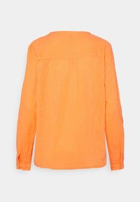 Camicia a maniche lunghe arancione in lino leggero. Il design posteriore presenta uno yoke e pieghe verticali. Polsini con bottoni e vestibilità rilassata.