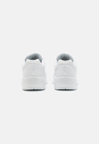 Baskets de sport blanches avec une tige synthétique lisse, un col rembourré et une semelle texturée. Accentué par de petites perforations sur les côtés.