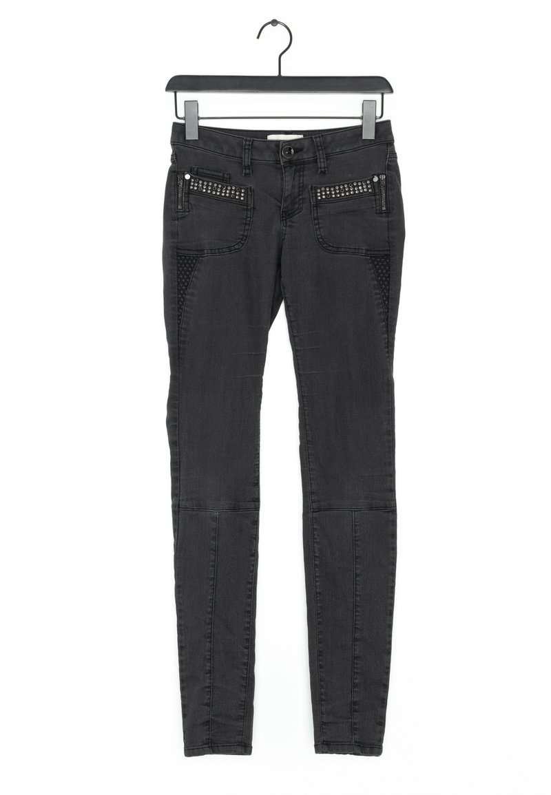 Pantalon noir slim fit avec zip et détails cloutés sur les poches avant, suspendu sur un cintre noir sur fond blanc.