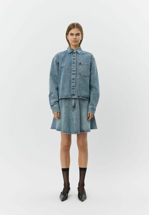 Kurtka dżinsowa z kołnierzem i przednią kieszenią, w zestawie z rozkloszowaną spódnicą dżinsową. Jasnoniebieski kolor, surowy brzeg i kontrastowe przeszycia.