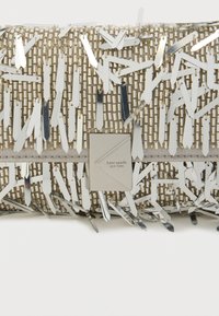 Ασημένια, υφασμένη τσάντα με αντανακλαστικές πινελιές και υφή στην επιφάνεια. Διαθέτει τετράγωνη πλακέτα λογότυπου και μεταλλικές λωρίδες διαφόρων μηκών.