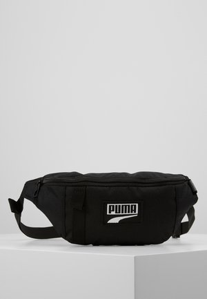 Schwarze Puma-Gürteltasche mit Frontreißverschlusstasche und verstellbarem Riemen auf weißer Oberfläche vor grauem Hintergrund.