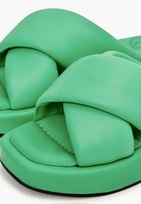 Groene slide-sandalen met een kruisdraai ontwerp, een gladde matte textuur en een zachte binnenzool met contrasterende stiksels op een dikke zool.