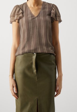Vrouw draagt een bruin gebloemde korte mouwen blouse met pofmouwen en een olijfgroene hoge taille rok met een split aan de voorkant.
