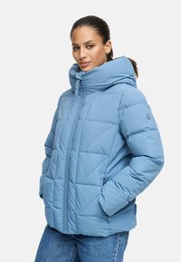 Vadderad blå jacka med hög krage och huva, med dragkedjestängning, diagonala kviltningar och sidfickor.