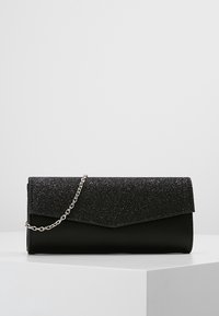 Pochette noire avec un rabat scintillant, dotée d'une bandoulière en chaîne argentée. Texture lisse au fond, finition mate sur le rabat.