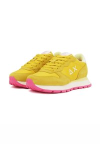 Gelbe Wildleder- und Stoff-Sneaker mit rosa Gummisohlen, ausgestattet mit einem weißen Akzent, einem dreieckigen Logo an der Seite und einem traditionellen Schnürdesign.