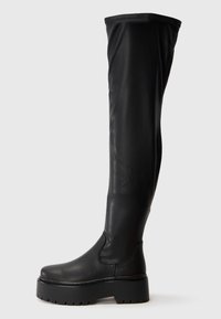 Sorte over-the-knee støvler laget av glatt syntetisk materiale. Har en rund tå og chunky plattformsåle med teksturert såle.
