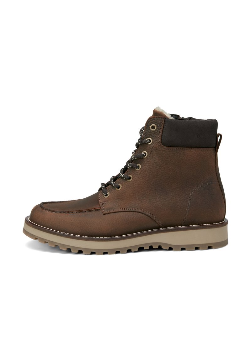 Stivale alla caviglia in pelle marrone con colletto imbottito, occhielli in metallo e suola in gomma beige a contrasto caratterizzata da un motivo antiscivolo texturizzato.