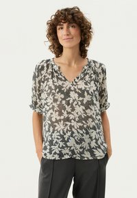 Lettet, blomsterpræget bluse med V-hals og korte, oprullede ærmer, der har sort og crème farver på et struktureret stof.