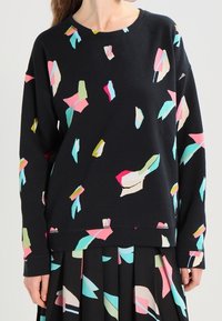 Zwarte sweatshirt met kleurrijke abstracte patronen in roze, turkoois en geel. Lange mouwen en ronde hals, relaxte pasvorm, zachte textuur.
