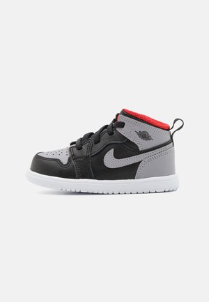 Sneaker alta nera e grigia con accenti rossi, dettagli in pelle testurizzata e mesh, punta tonda e suola in gomma bianca. Presenta una chiusura con lacci.