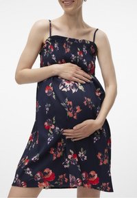 Abito floreale blu navy con corpetto arricciato e spalline sottili, caratterizzato da vivaci motivi floreali in rosso, rosa e verde. Adatto per l'abbigliamento premaman.