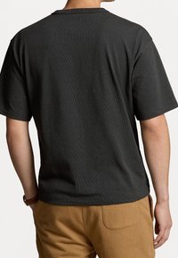 Ciemnoszary t-shirt z krótkim rękawem wykonany z miękkiego materiału, z klasycznym okrągłym dekoltem i luźnym krojem. Bez widocznych wzorów lub ozdób.