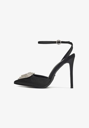 Melnas satīna augstpapēžu kurpes ar smailu purngalu, potītes siksniņu un dārgakmeņiem rotātu purngala daļu. Gluda tekstūra, elegants dizains.