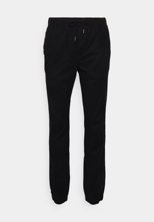 Schwarze Jogginghosen aus weichem Stoff, mit elastischem Bund und Kordelzug, seitlichen Taschen und schmal zulaufenden Bündchen.