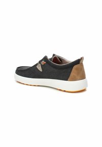 Zapato de lona negro con acentos de ante gris, suela de goma blanca, detalles en naranja y un forro de malla transpirable. Presenta cordones y una puntera redondeada.
