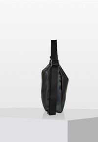 Borsa a tracolla nera in pelle con finitura texturizzata, caratterizzata da una vasta tracolla regolabile e una forma elegante e angolare.
